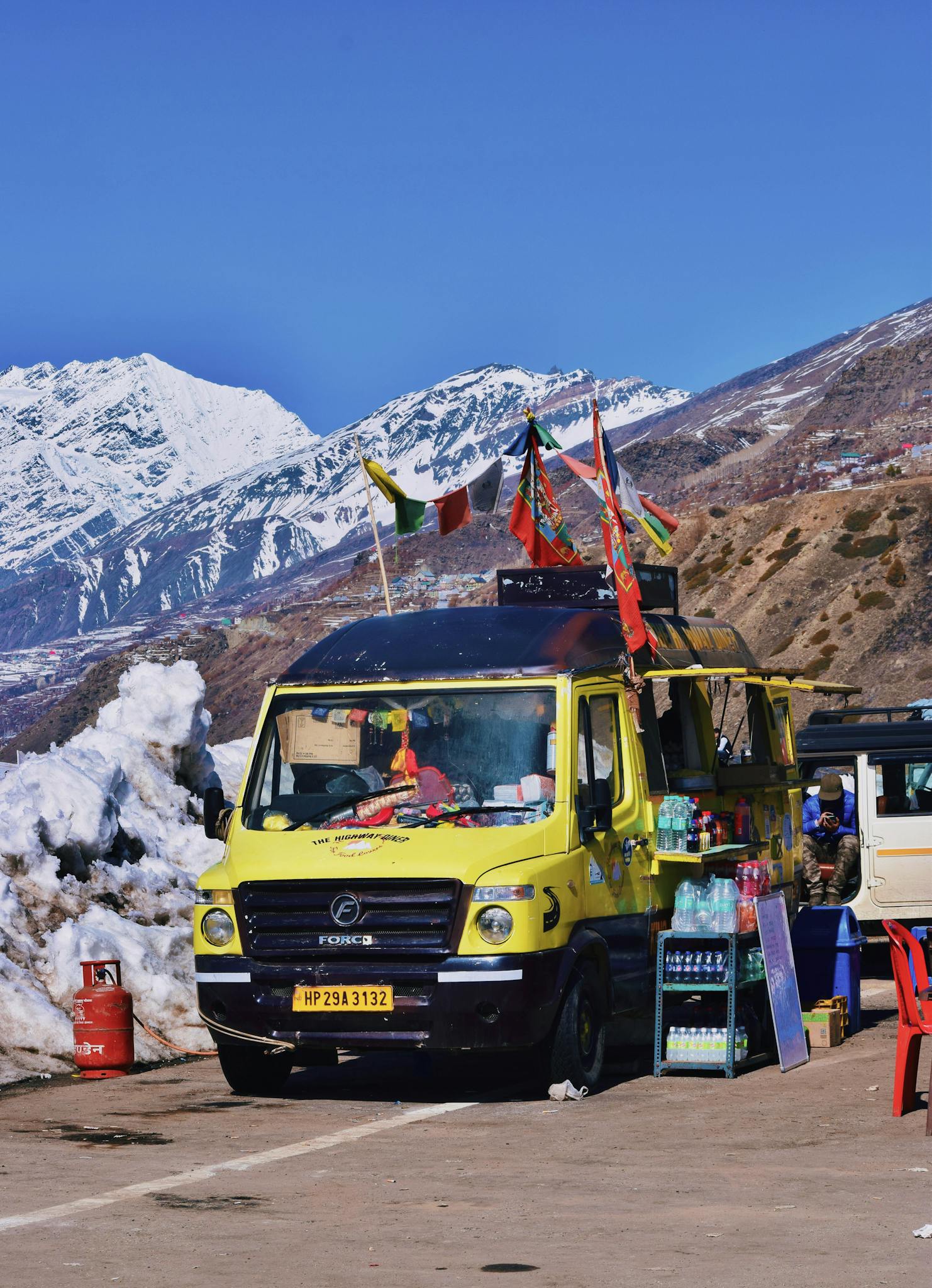 A colorful food truck stationed amidst snow-covered mountains, offering refreshments.